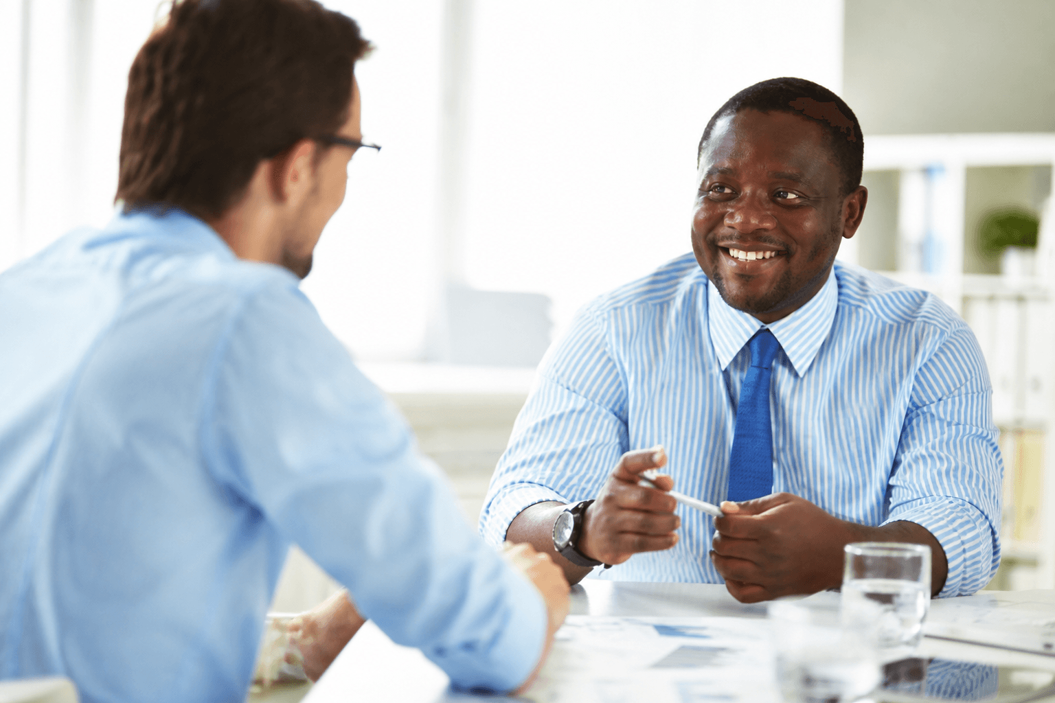 Two colleagues meeting at a desk in a bright office